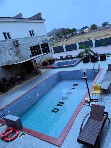 a swimming pool with two chairs and a building at Enseno Hotel in Karshi