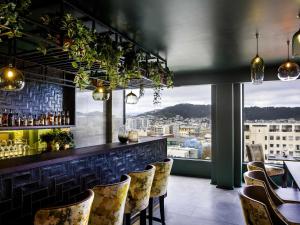 a bar with chairs and a view of a city at Mövenpick Hotel Wellington in Wellington