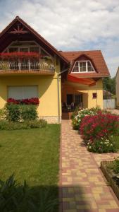 a yellow house with flowers in a yard at Nádor Apartmanok in Kaposvár