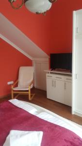 a red room with a chair and a television at Nádor Apartmanok in Kaposvár