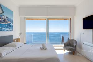 a bedroom with a bed and a chair and a large window at Villa Eze Vue Mer in Éze