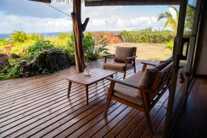 a wooden deck with chairs and a table and an umbrella at Kona Koa Lodge in Hanga Roa +85 photos