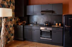 a kitchen with gray cabinets and a sink and a stove at Le Nid Fleuri - Séjour familial à Tournai in Tournai +27 photos