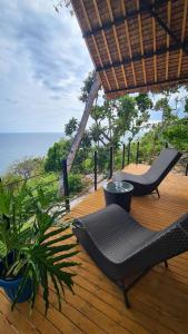 a wooden deck with chairs and a table and the ocean at Balay Mariposa in Langagan