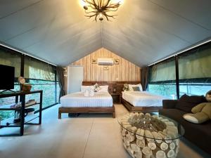 a room with two beds and a couch and a tv at Mont Blanc Base Camp Khaoyai in Pak Chong