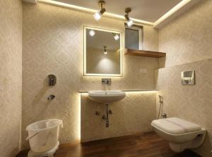 a bathroom with a sink and a toilet and a mirror at Hotel Olive Aero Suites Near Delhi IGI Airport in New Delhi