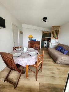 a living room with a table and a couch at Les flos bleus in La Bernerie-en-Retz +5 photos