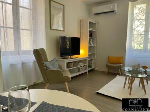 a living room with a tv and a chair and a table at Appartement scandinave élégant, Domaine Cornevent Lyon, parc & piscine in Vernaison