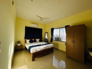 a bedroom with a bed with yellow walls and a window at Royal Inn in Mysore