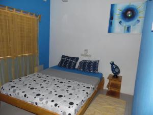 a bedroom with a bed with a blue wall at La Paillotte in Palimé