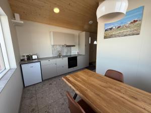 a kitchen with a wooden table and a wooden ceiling at Svalbarð guesthouse in Hvammstangi