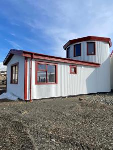 a small white house with red trim on a lot at Svalbarð guesthouse in Hvammstangi