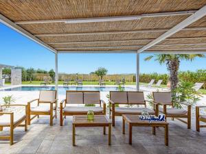 a patio with chairs and tables and a pool at Villa Kika by holiday World in Ispica