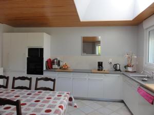 a kitchen with white cabinets and a sink and a table at Gîte G337 in Quibou +12 photos