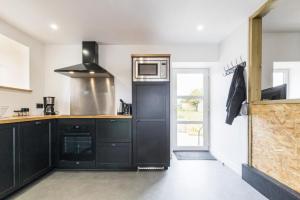 a kitchen with black cabinets and a microwave at Gîte G593 in Le Val-Saint-Père