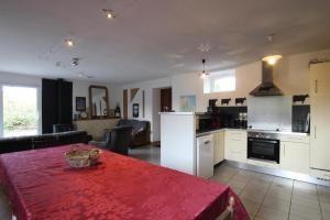 a kitchen and living room with a red table in it at Gîte G40 in Marchésieux +8 photos
