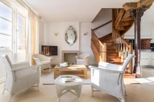 a living room with white chairs and a staircase at Gîte G4 in Barfleur