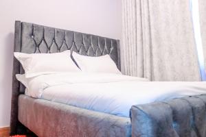 a bed with a gray headboard and white pillows at Maggy Homes in Marimbeti