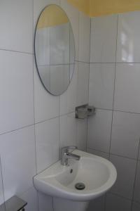 a white bathroom with a sink and a mirror at Kibale Eco-Home in Bigodi