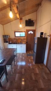 a kitchen with a table and a refrigerator at Cabañas 2 Aliwen Lonquimay in Lonquimay +3 photos