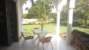 a table and chairs on a porch with a view of a yard at Egg Botanical View in Entebbe