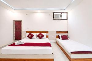 two beds in a room with white walls and red pillows at Premium-Ram-Krishna-Palace in Ayodhya