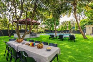 a table and chairs in a yard with trees at EKOSTAY Gold - Amara Villa in Alibaug