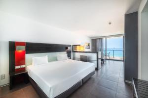 a bedroom with a large white bed with a view of the ocean at RR Hotel da Rocha in Portimão +65 photos