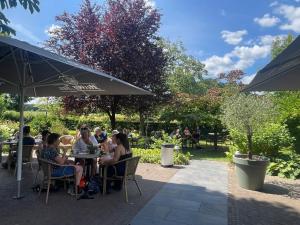 a group of people sitting at tables under an umbrella at Wildenborcherhof in Vorden