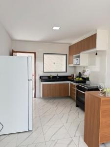 a kitchen with wooden cabinets and a white refrigerator at Casa Privativa Jacuzzi em Linhares in Linhares
