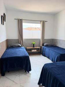 two beds in a room with a window at Casa Privativa Jacuzzi em Linhares in Linhares