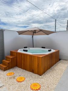 a hot tub with an umbrella on a building at Casa Privativa Jacuzzi em Linhares in Linhares