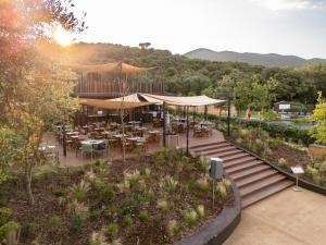 a restaurant with tables and umbrellas in a garden at Club del Sole Stella del Mare Family Collection in Castiglione della Pescaia