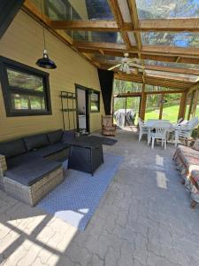 eine Terrasse mit Sofa, Fernseher und Tisch in der Unterkunft Chalet le Léandre in Cabano