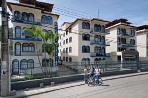 two people on a bike in front of buildings at Kitnet na rua da UFV com Smart TV e Garagem in Viçosa