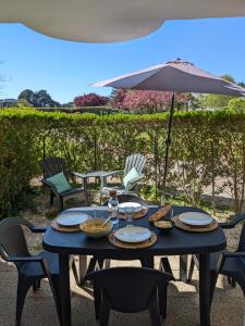 a blue table with plates of food and an umbrella at Studio l'Oasis - Piscine, plage de La Baule 10 min in Guérande