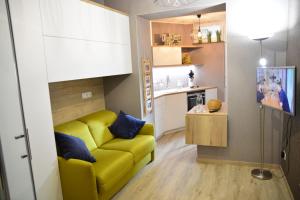 a living room with a yellow couch and a kitchen at Lodge 33 Eupen in Eupen