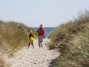 a man and a child walking on a beach at DCU-Camping Ålbæk Strand in Ålbæk +9 photos