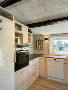 a kitchen with white cabinets and a large window at Summer House With Wilderness Bath By Kårup Forest in Fårevejle