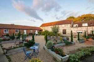 a garden with tables and chairs in front of a building at The Saddlery in Sewerby