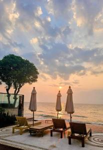 a group of chairs and umbrellas next to the ocean at Vimanlay 84m style balinais - 2 chambres - plage, piscines in Cha Am