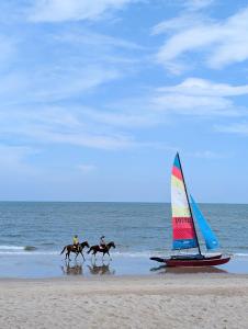 three people riding horses on the beach with a sail boat at Vimanlay 84m style balinais - 2 chambres - plage, piscines in Cha Am