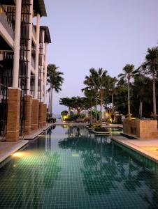 a swimming pool in front of a building with palm trees at Vimanlay 84m style balinais - 2 chambres - plage, piscines in Cha Am