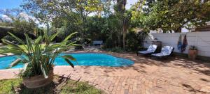 a small swimming pool with two chairs and a plant at Clarents Cottage in Somerset West