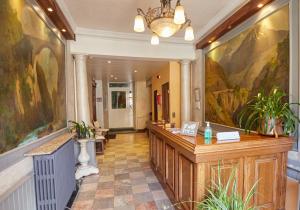 a hotel lobby with a reception desk and a painting at Hôtel Panoramic et des Bains in Luz-Saint-Sauveur