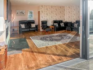 a living room with black leather furniture and wooden floors at Grey Rocks House in Kippford +36 photos