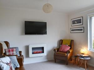 a living room with a tv and two chairs at Summit in Oban