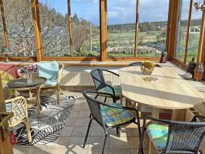 a room with tables and chairs and a large window at Juniper Cottage in Buckie