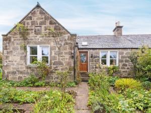 an old stone cottage with a front door and windows at Juniper Cottage in Buckie