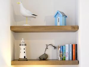 a shelf with a bird and a lighthouse and books at Castle Street in Criccieth